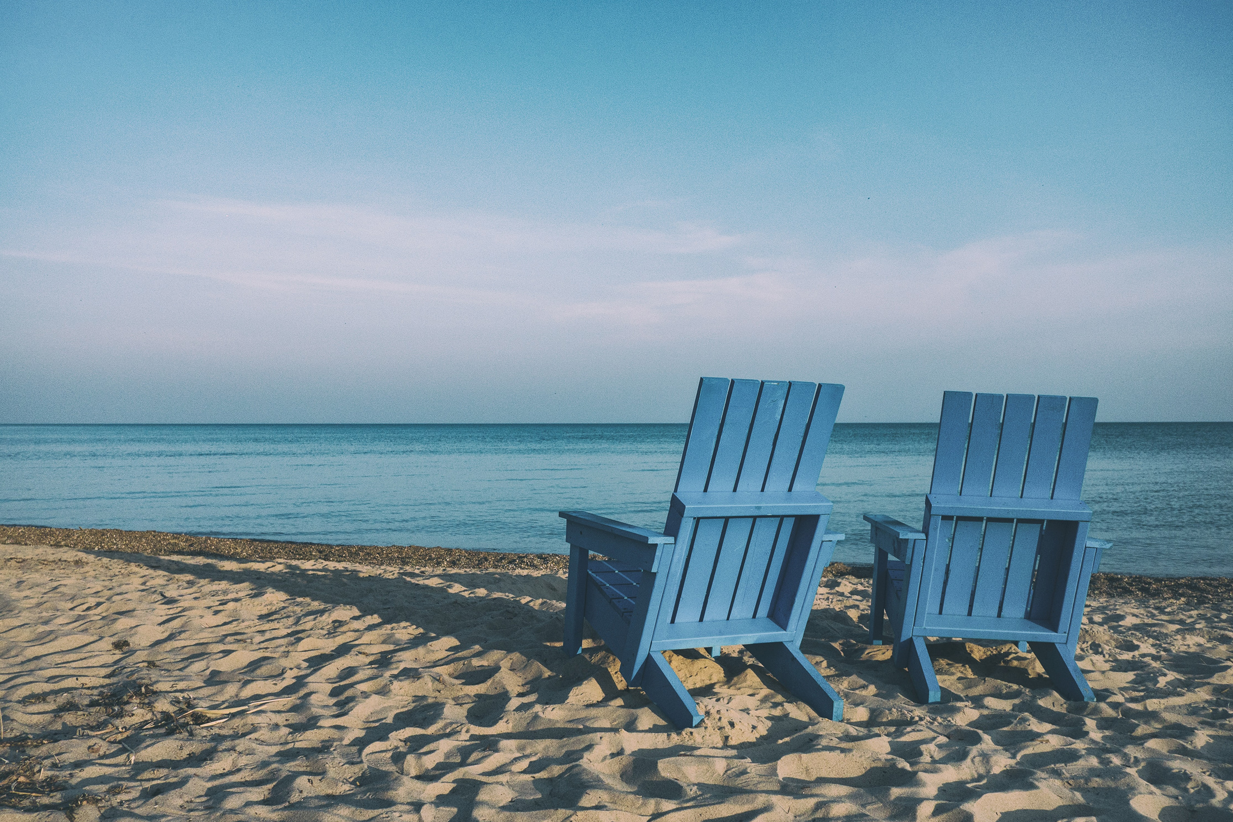 two patio chairs on the beach overlooking the ocean